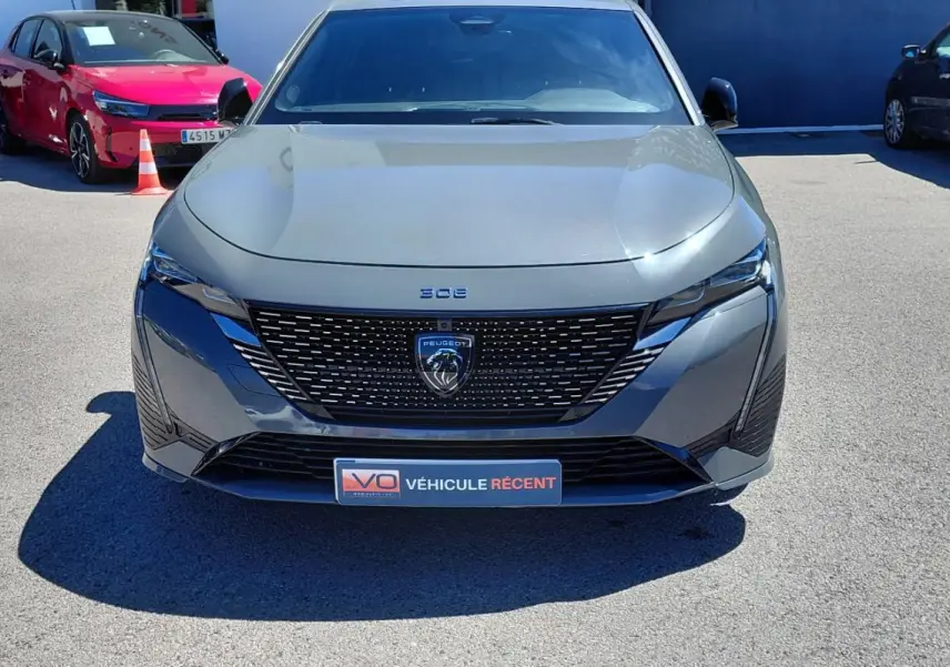 Vue avant d'une Peugeot 308 Hybrid 145 e-DCS6 GT gris métallisé avec calandre noire et logo lion central.