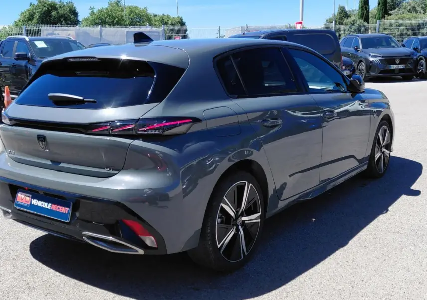 Vue 3/4 arrière droit d’une Peugeot 308 Hybrid 145 e-DCS6 GT gris avec jantes alliage 18 pouces et feux arrière LED distinctifs.