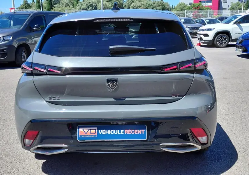 Vue arrière d’une Peugeot 308 Hybrid 145 e-DCS6 GT gris avec feux LED et double sortie d’échappement intégrée.