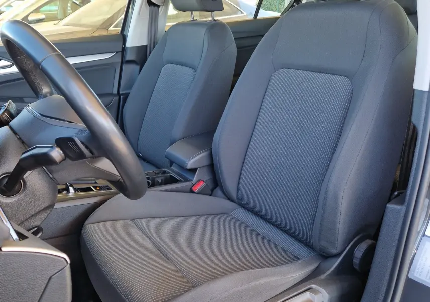 Vue intérieure côté conducteur de la Volkswagen Golf A8 gris Urano 2023, sièges tissu gris et volant noir visible.