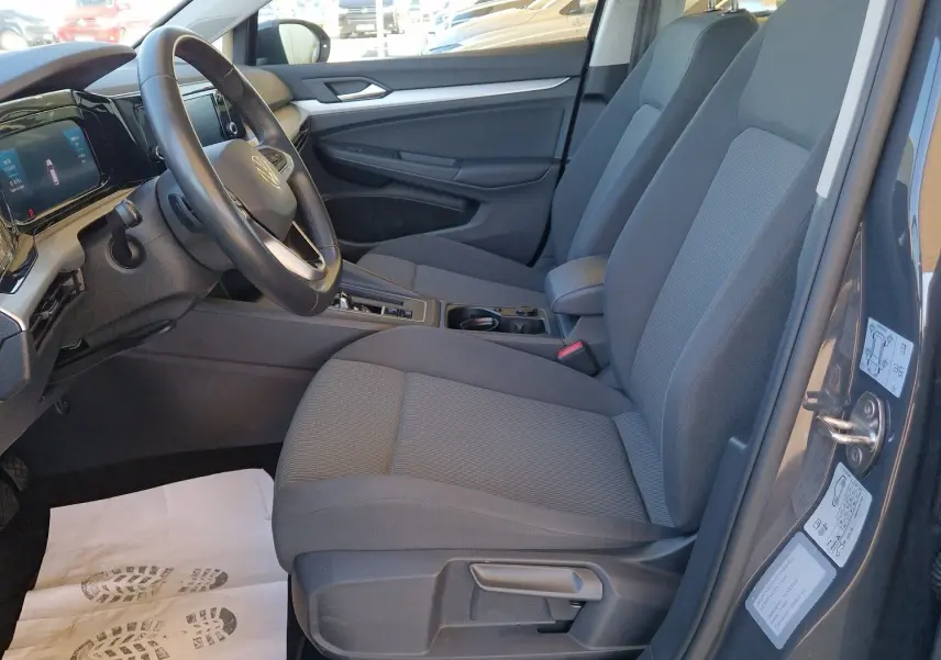 Intérieur côté conducteur d'une Volkswagen Golf A8 gris Urano 2023, sièges tissu gris et tableau de bord moderne.