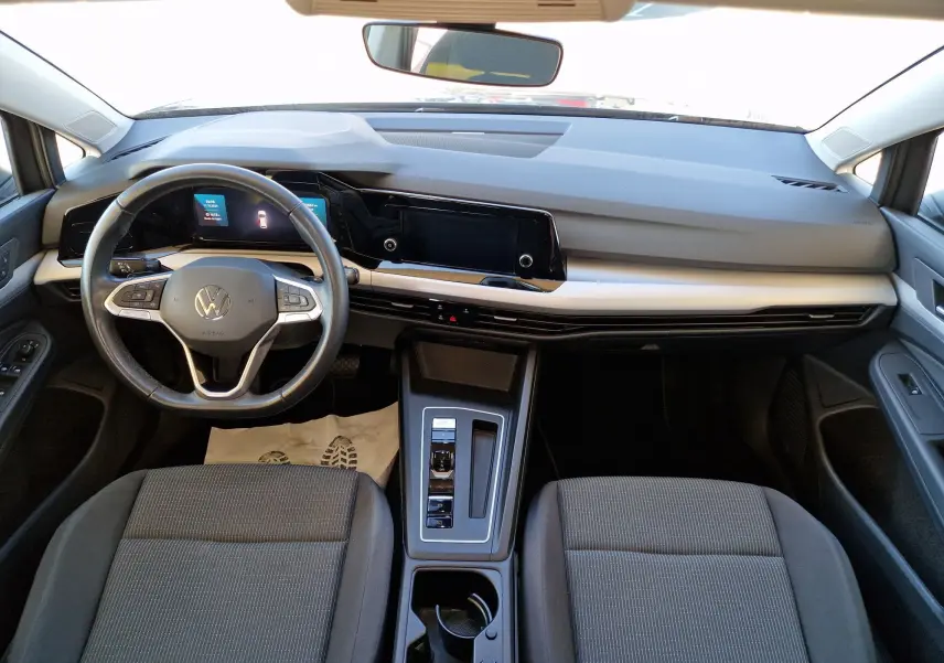 Vue intérieure avant de la Volkswagen Golf A8 2023 avec tableau de bord moderne et sièges gris, volant multifonction et écran tactile.