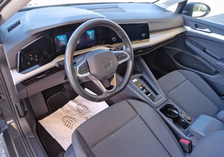 Vue intérieure côté conducteur de la Volkswagen Golf A8 2023, tableau de bord moderne et sièges gris foncé.