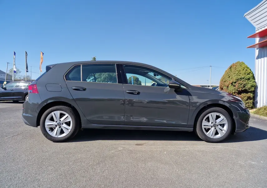 Profil côté gauche d'une Volkswagen Golf A8 2023 gris Urano, avec jantes alliage et lignes épurées visibles.