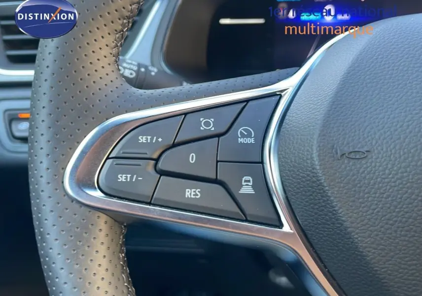 Gros plan sur les commandes au volant perforé du Renault Captur E-Tech gris Cassiopée, mettant en valeur les boutons de régulateur.