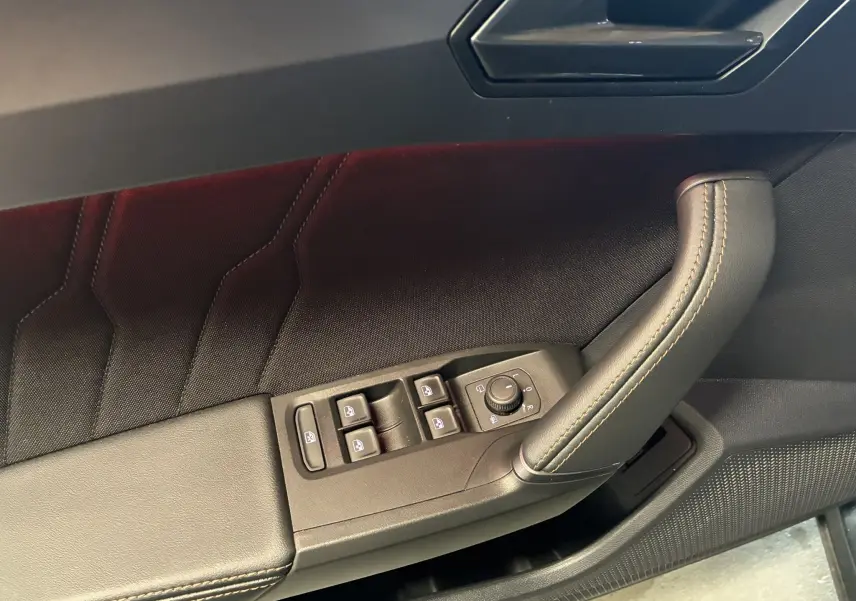 Gros plan sur la garniture de porte côté conducteur du CUPRA Formentor gris foncé, avec commandes électriques et poignée cuir noir.