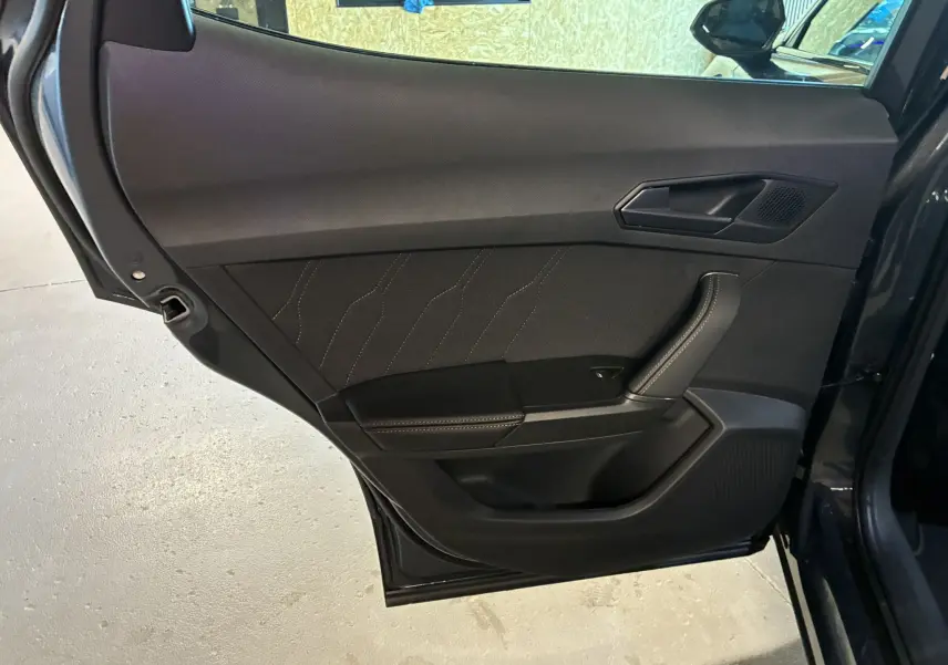 Porte arrière côté gauche ouverte d'un CUPRA Formentor gris foncé, intérieur noir avec surpiqûres contrastées.