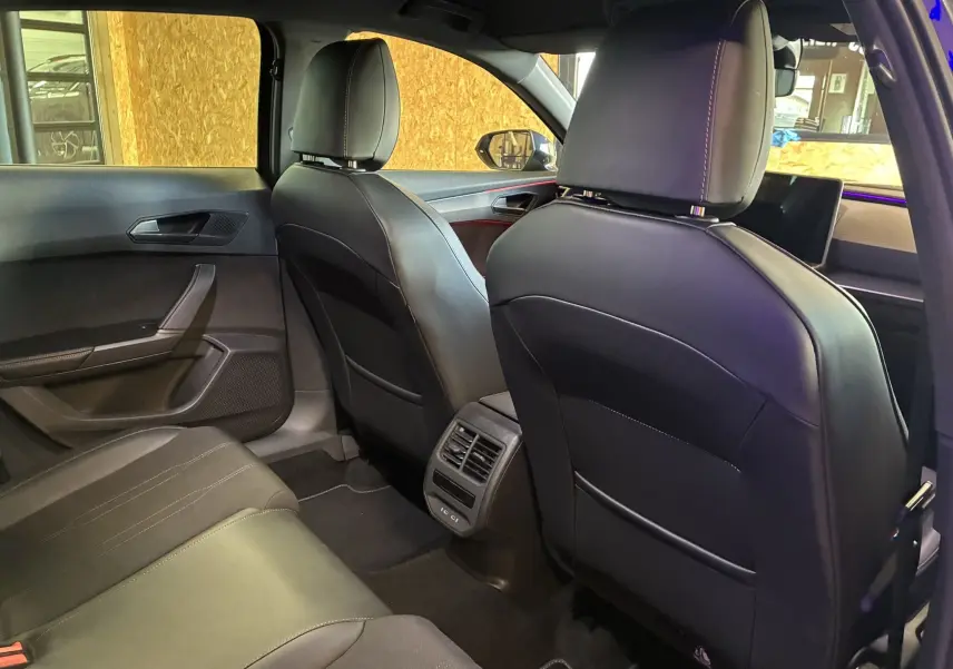 Vue intérieure arrière du CUPRA Formentor 2024, sièges en cuir noir et aérateurs centraux entre les sièges avant.