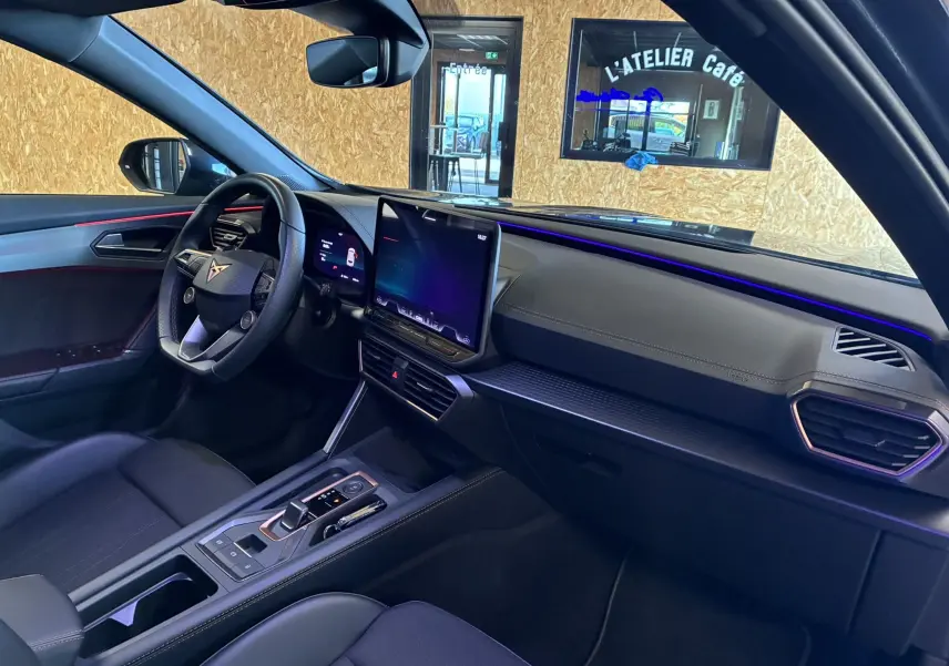 Intérieur noir du CUPRA Formentor 2024 vu côté conducteur, avec tableau de bord moderne et éclairage d'ambiance violet.