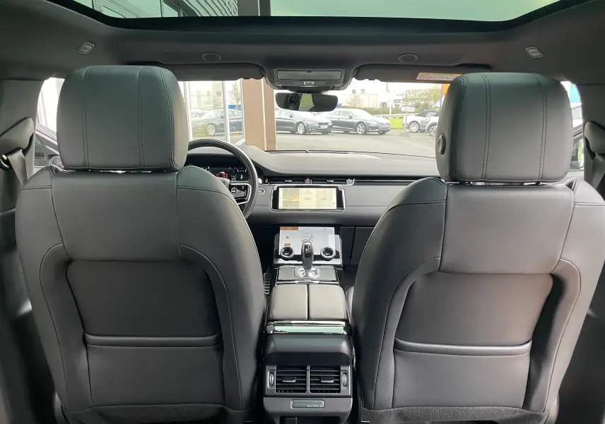 Vue intérieure arrière du Range Rover Evoque 200D SE R-Dynamic 2021 en cuir noir, avec tableau de bord et écran tactile visibles.