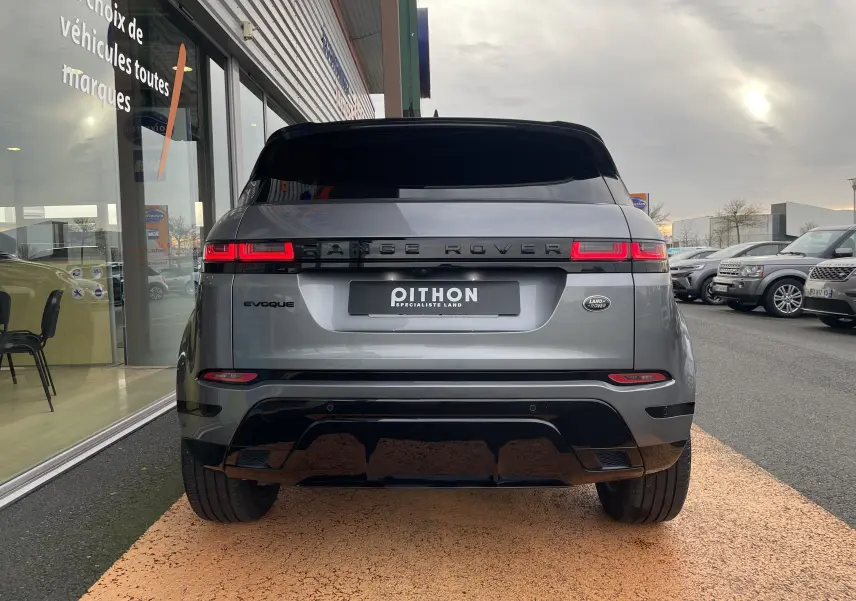 Vue arrière d'un Range Rover Evoque 200D SE R-Dynamic gris Eiger avec feux LED allumés, stationné devant un showroom.