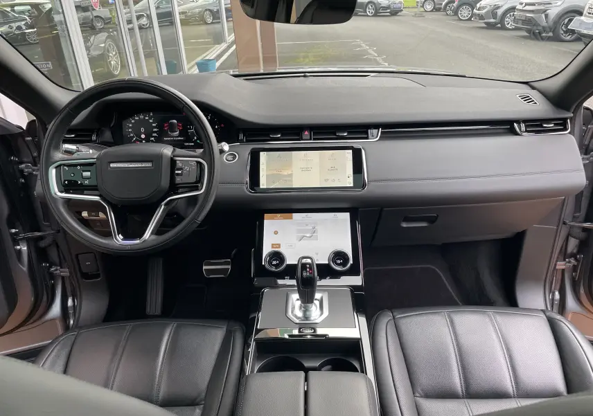 Vue intérieure avant du Range Rover Evoque 200D SE R-Dynamic en Eiger Grey, tableau de bord moderne avec écran tactile et cuir noir.