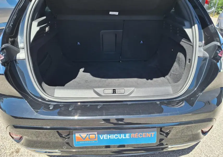 Coffre ouvert vu de l'arrière d'une Peugeot 308 Hybrid 145 e-DCS6 GT noire, montrant un espace de chargement vide.