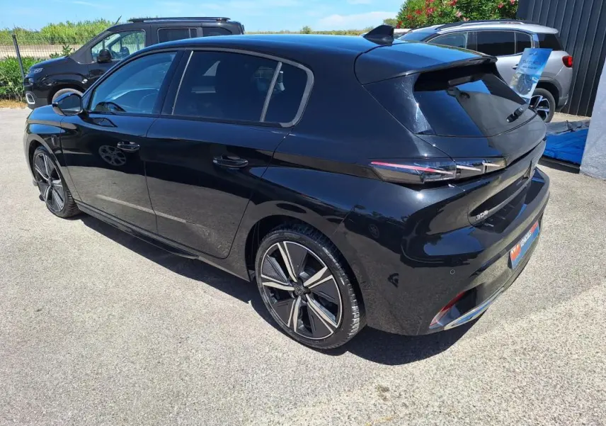 Vue 3/4 arrière droite d'une Peugeot 308 Hybrid 145 e-DCS6 GT noire avec jantes alliage 18 pouces et vitres teintées.