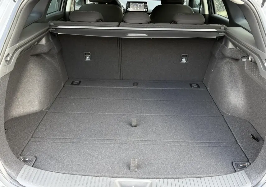 Vue intérieure du coffre spacieux d'une Hyundai i30 SW T-GDI 120 Modern gris argent avec cache-bagages déployé.