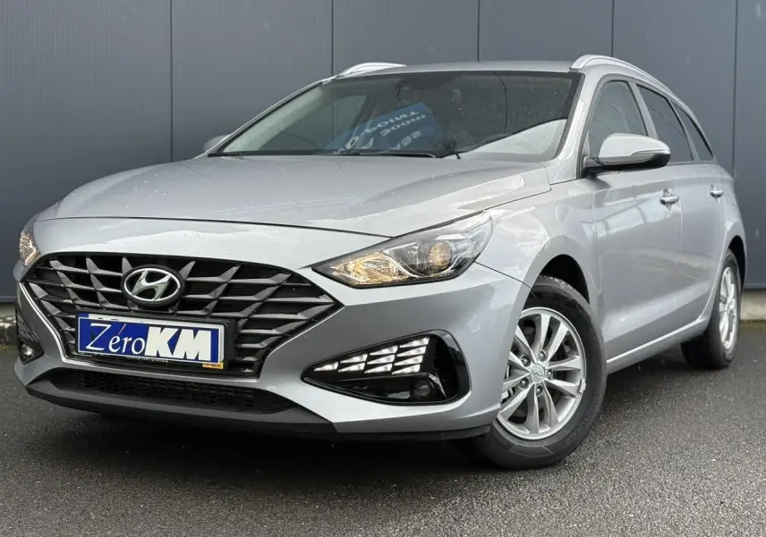Hyundai i30 SW T-GDI 120 Modern gris argent en 3/4 avant droit, avec calandre noire et jantes alliage.