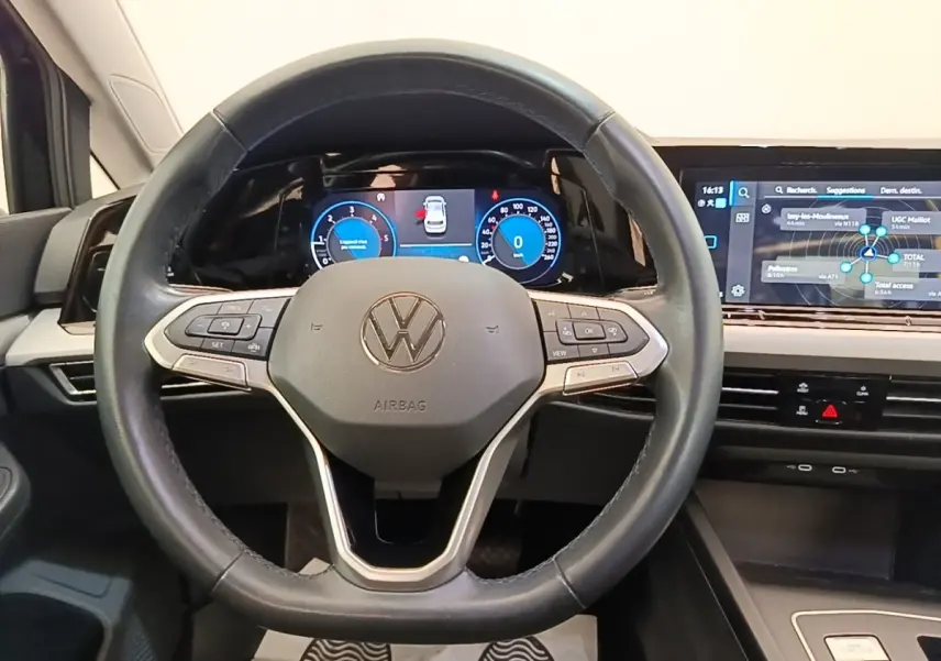 Vue intérieure centrée sur le volant cuir de la Volkswagen Golf 2023 avec tableau de bord digital et écran tactile.