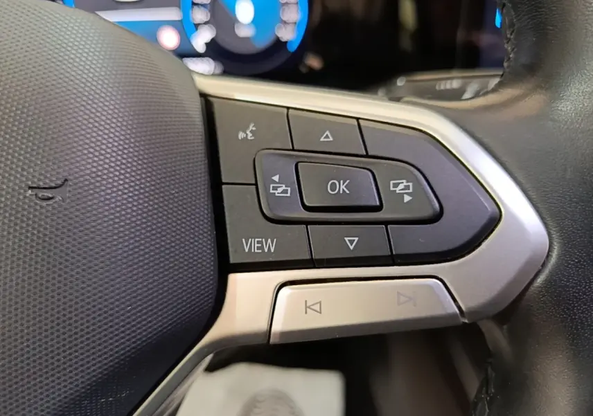 Gros plan sur les commandes multifonctions côté gauche du volant noir de la Volkswagen Golf 2023, affichage digital en arrière-plan.