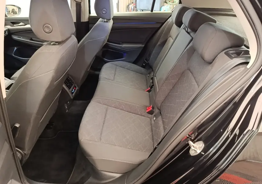 Vue côté gauche arrière de l’habitacle d’une Volkswagen Golf noire 2023, montrant la banquette tissu et les sièges avant.