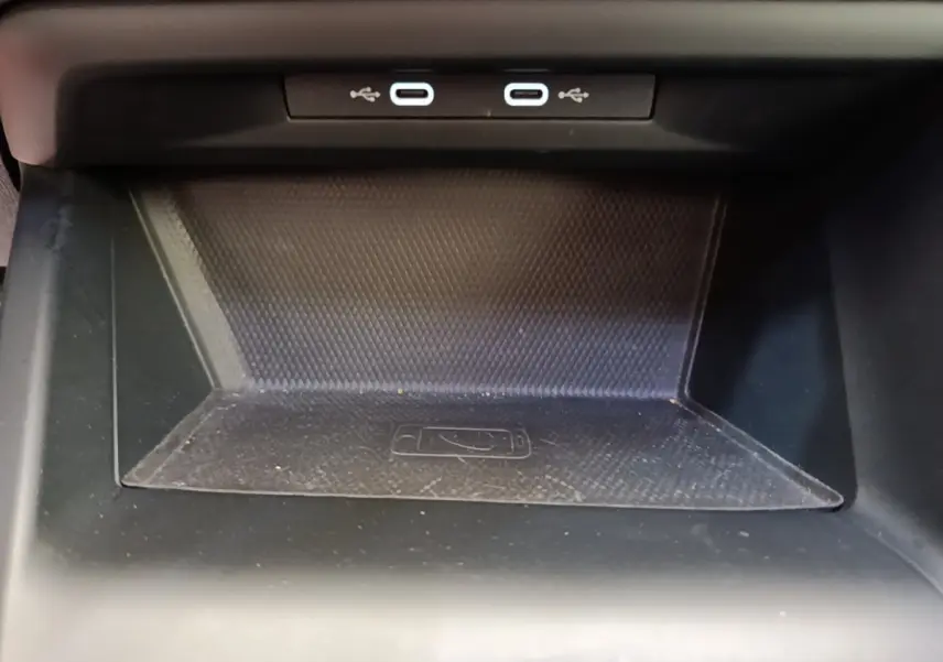 Vue rapprochée de la zone de recharge à induction noire avec deux ports USB-C dans une Volkswagen Golf 2023.