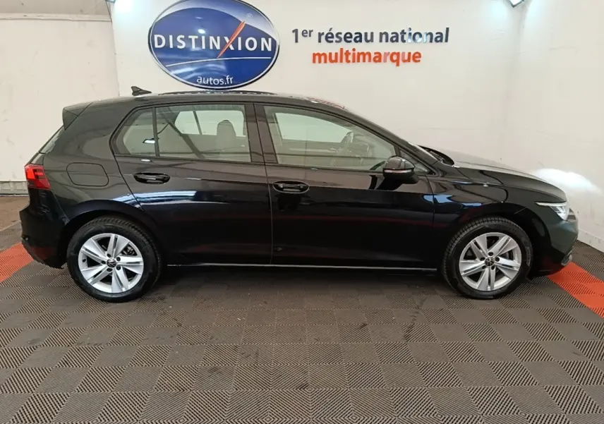 Profil droit d'une Volkswagen Golf noire 2023 garée en intérieur avec jantes alliage et vitres teintées.