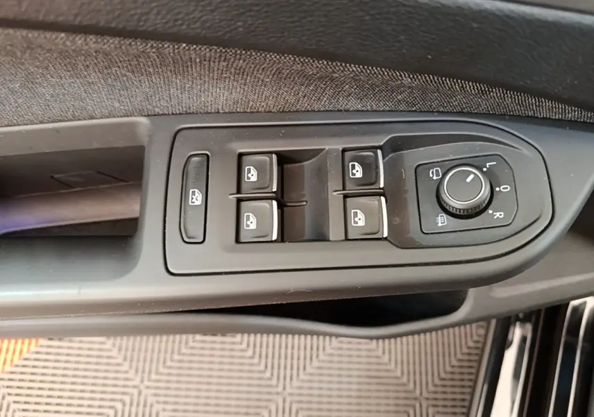 Gros plan sur les commandes de lève-vitres et rétroviseurs côté conducteur d'une Volkswagen Golf noire 2023.