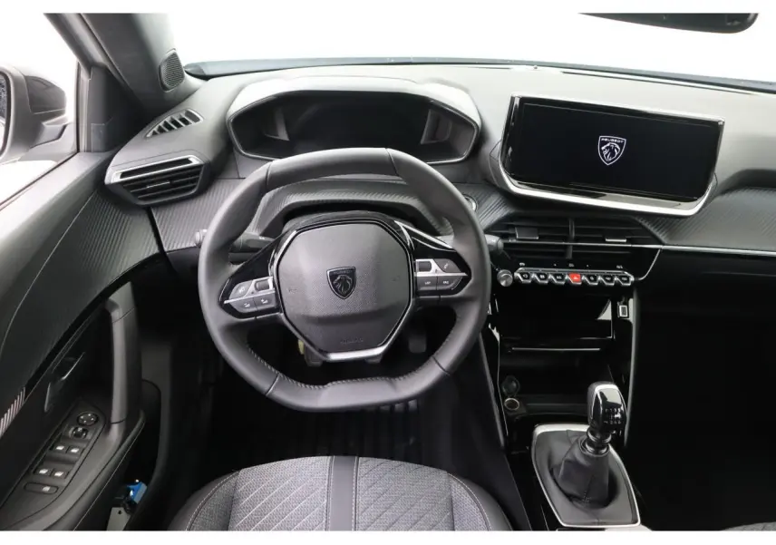 Vue intérieure centrée sur le volant et la console centrale du Peugeot 2008 blanc Okenite avec boîte manuelle.
