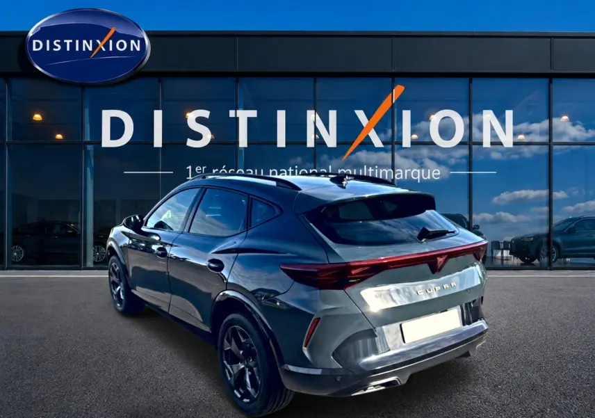 Vue 3/4 arrière droite du CUPRA Formentor bleu fjord 2026 avec feux arrière LED et jantes 18 pouces devant un showroom Distinxion.