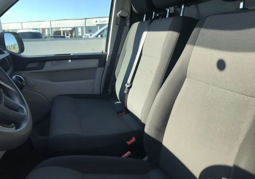 Intérieur du Volkswagen Transporter T6 2016, vue côté gauche sur les sièges avant gris et la portière beige.