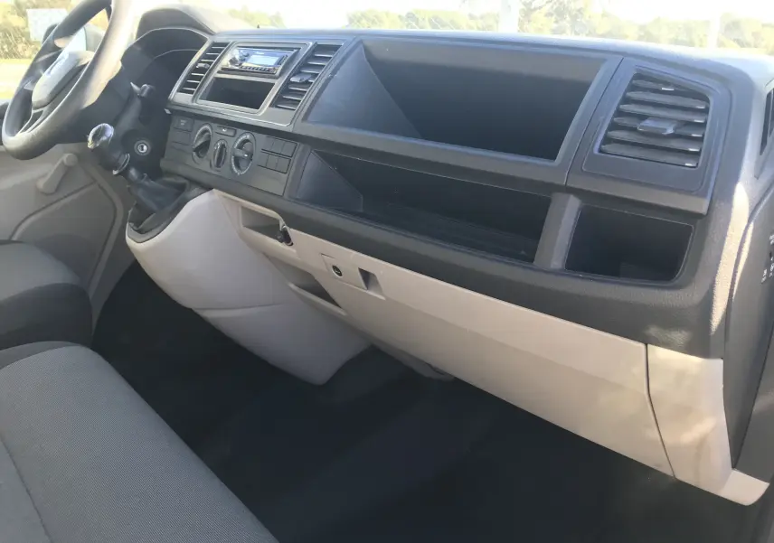 Intérieur du Volkswagen Transporter T6 L2 H1 2016, tableau de bord gris et beige vu côté passager avec levier de vitesses manuel.