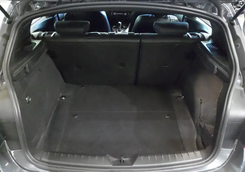 Coffre ouvert d'une BMW Série 1 F21 LCI gris, vue arrière montrant l'espace de chargement et l'intérieur noir.