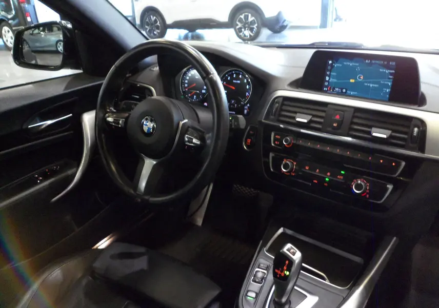 Intérieur noir de la BMW Série 1 F21 118i 2019, vue côté conducteur avec tableau de bord et écran navigation.