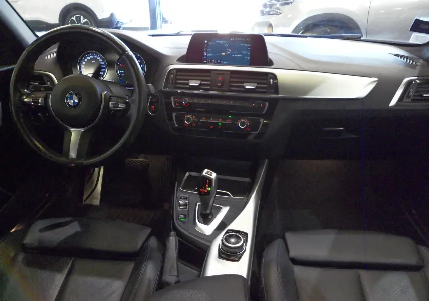 Intérieur de BMW Série 1 F21 LCI 118i 2019, vue du poste de conduite avec tableau de bord et console centrale en cuir noir.