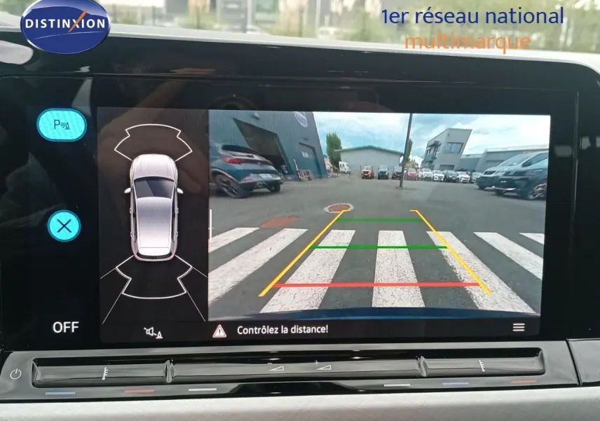 Écran intérieur affichant la caméra de recul avec vue arrière et lignes de guidage d'une Volkswagen Golf VIII bleu Atlantique.