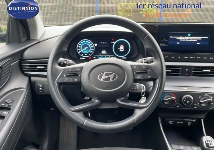 Vue intérieure du tableau de bord et volant cuir de la Hyundai i20 2025 avec écran digital et commandes au volant.