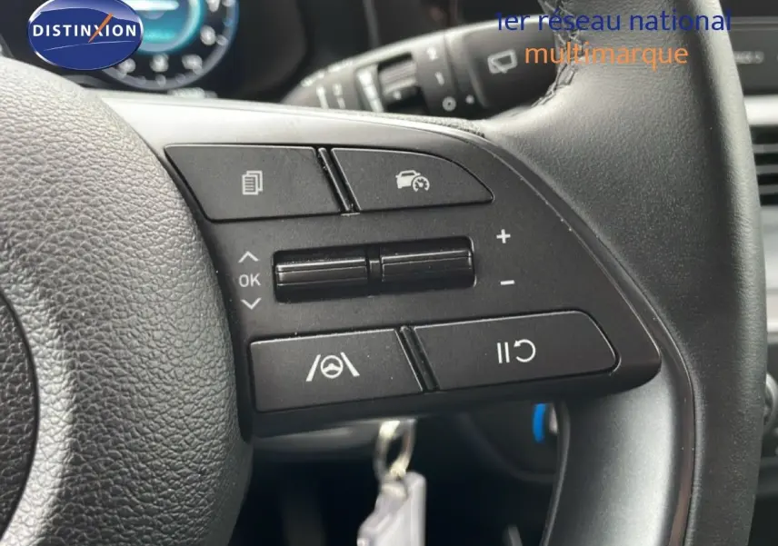 Gros plan sur les commandes au volant noir de la Hyundai i20 2025, version 1.0 TGDI en tissu et cuir.