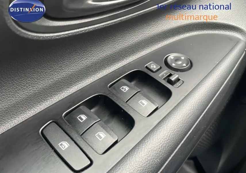 Gros plan sur les commandes des vitres électriques côté conducteur d'une Hyundai i20 2025 finition Klass noire.