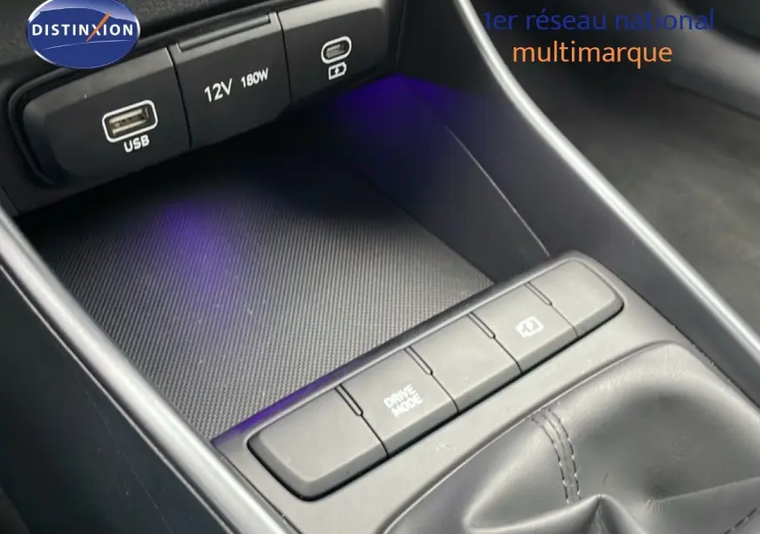 Gros plan sur la console centrale avec prises USB, bouton Drive Mode et finition noire intérieure de la Hyundai i20 2025.