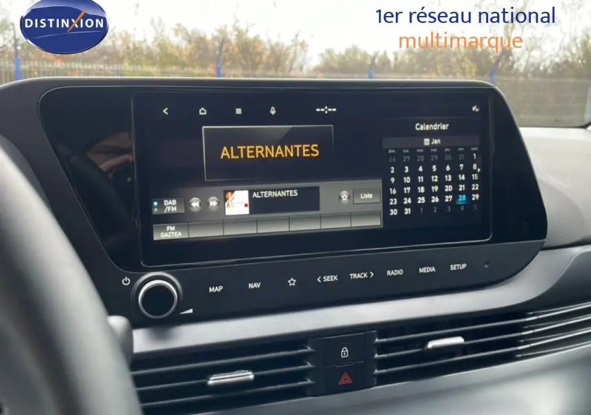 Écran tactile central du tableau de bord de la Hyundai i20 2025, affichant radio et calendrier, intérieur noir moderne.