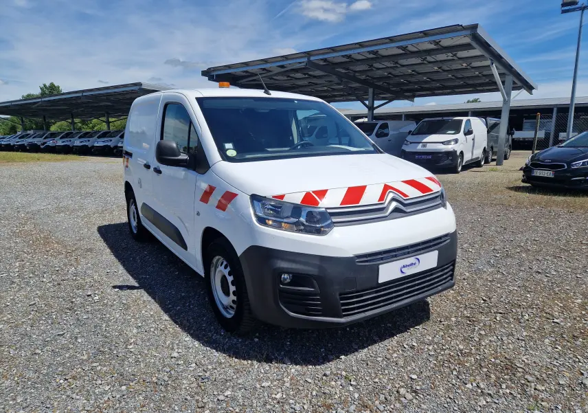 Citroën Berlingo blanc en 3/4 avant droit avec bandes rouges réfléchissantes et gyrophare orange sur le toit.