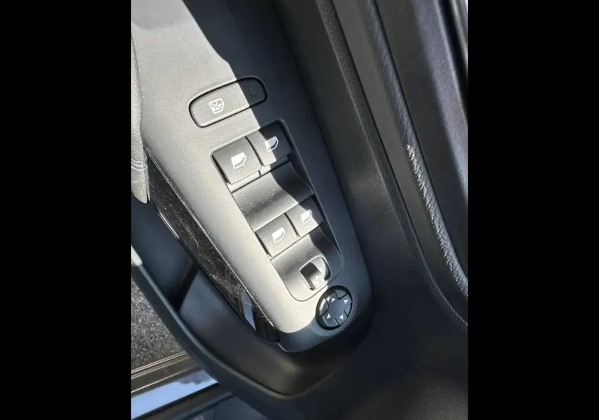 Gros plan sur les commandes des vitres électriques côté conducteur du Citroën C5 Aircross gris Platinium, intérieur noir.