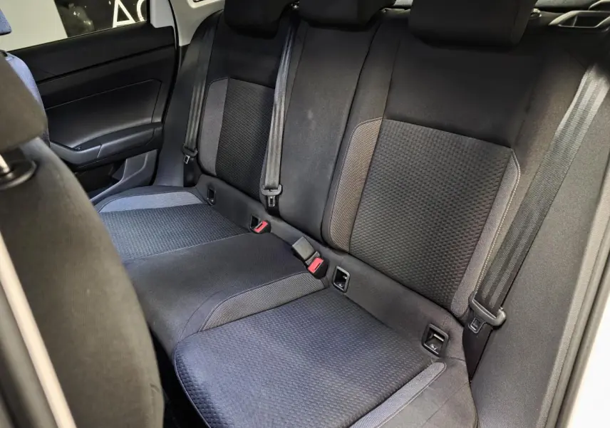 Vue intérieure de la banquette arrière en tissu noir et gris du Volkswagen Taigo 2024, avec ceintures de sécurité visibles.