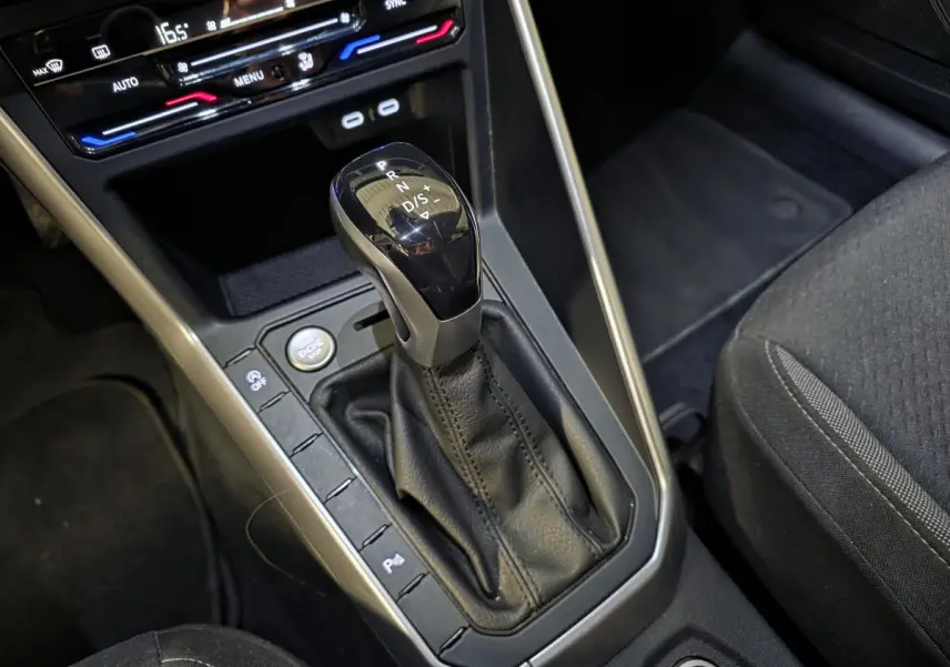 Le levier de vitesses automatique noir et argenté de la Volkswagen Taigo 2024, avec console centrale et siège tissu gris.