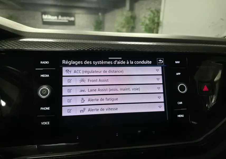 Écran tactile intérieur du Volkswagen Taigo blanc montrant les réglages d'aide à la conduite.