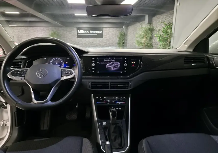 Vue intérieure frontale du tableau de bord et volant cuir noir d'un Volkswagen Taigo 2024 avec écran tactile et levier de boîte auto