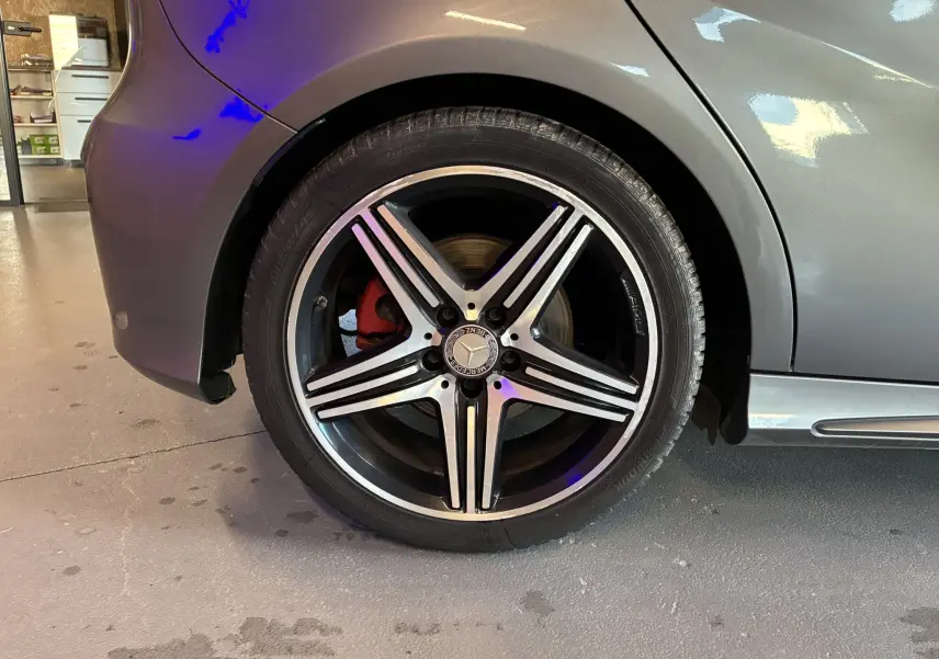 Gros plan sur la roue arrière droite gris métallisé d'une Mercedes Classe A 250 AMG Sport avec jante alliage 5 branches et étrier de frein rouge.