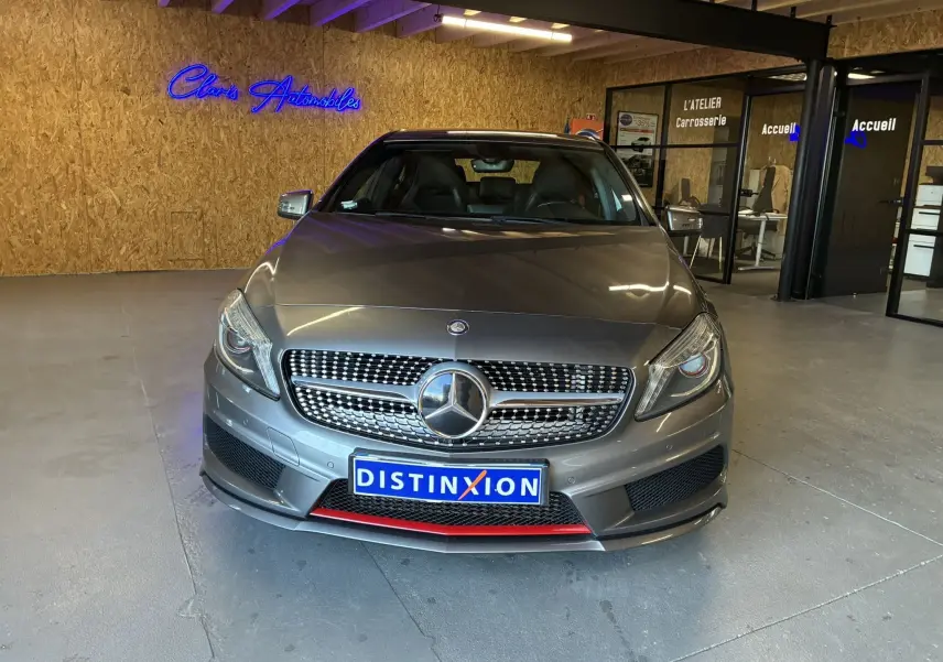 Vue avant d'une Mercedes Classe A 250 AMG Sport gris métallisé avec calandre distinctive et détail rouge sur le pare-chocs.