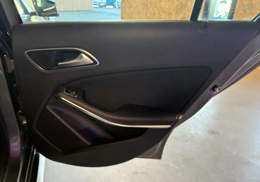 Gros plan sur la porte arrière gauche intérieure noire d'une Mercedes Classe A 250 AMG Sport gris 2014.