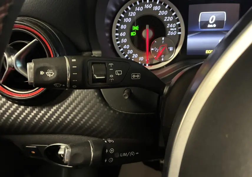 Gros plan sur le combiné d'instruments et les commandes au volant d'une Mercedes Classe A 250 AMG Sport gris, intérieur noir.