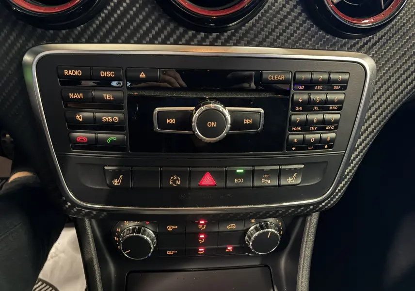 Console centrale de la Mercedes Classe A 250 AMG Sport 2014 avec commandes radio, climatisation et finition carbone noire.